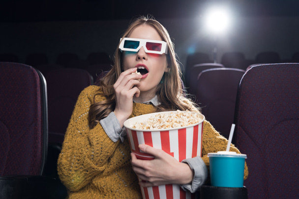 excited woman in 3d glasses eating popcorn and watching movie in cinema - Fotó, kép