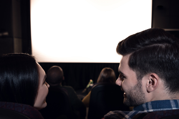 vista trasera de amigos sentados en el cine con pantalla blanca en blanco
  - Foto, Imagen