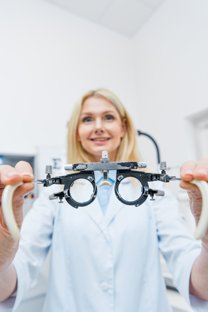 optician in white coat holding trial frame in clinic - Photo, Image
