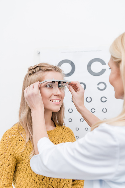 patient and oculist with trial frame and eye chart behind - Photo, Image