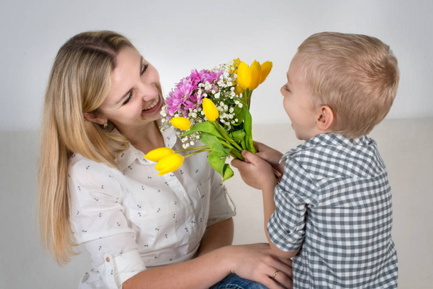 Син дарує коханій мамі гарний букет тюльпанів. Концепція святкування, жіночий день
. - Фото, зображення