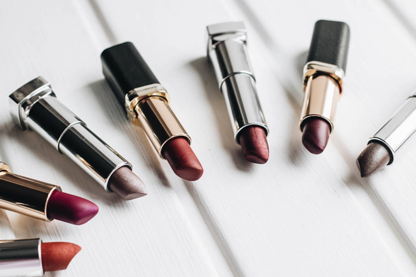 Lipsticks of different colors on wooden background - Foto, afbeelding