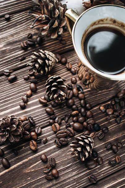 vista de cerca de granos de café tostados taza de café y conos de pino
 - Foto, Imagen