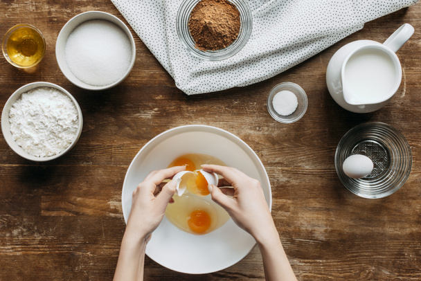 cropped shot of woman breaking eggs into bowl for baking - Photo, Image