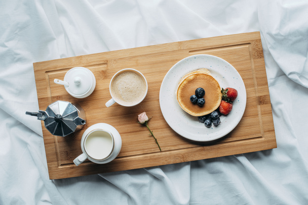 vista superior del desayuno en la cama con panqueques recién horneados y café en bandeja de madera
 - Foto, Imagen
