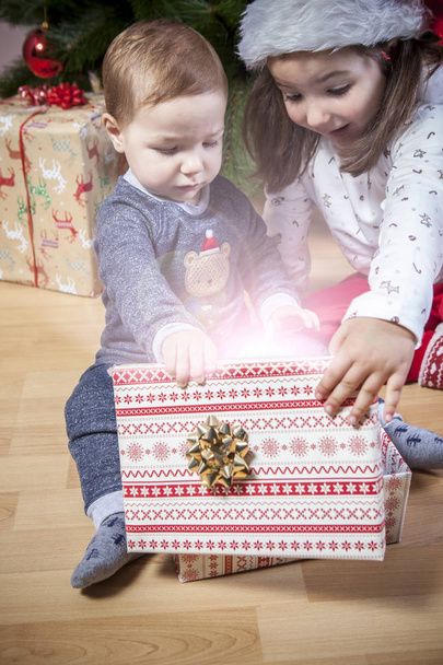 Kleine Brüder öffnen ihre Geschenke nahe am Weihnachtsbaum - Foto, Bild