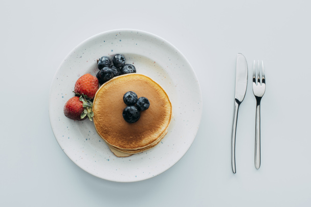 top view of pancakes with blueberries and strawberries on white table - Foto, Imagem