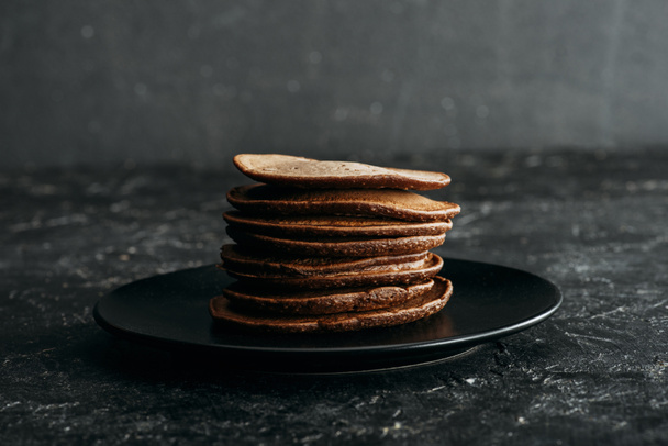 stapel van heerlijke chocolade pannenkoeken op zwarte plaat - Foto, afbeelding