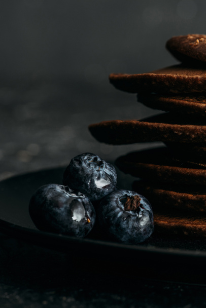 Close-up shot van verse bosbessen met gestapelde chocolade pannenkoeken - Foto, afbeelding