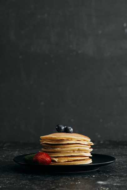 plate of delicious pancakes with berries on black concrete surface - 写真・画像
