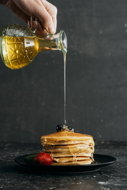 cropped shot of woman pouring maple syrup onto stack of freshly baked pancakes - Photo, Image