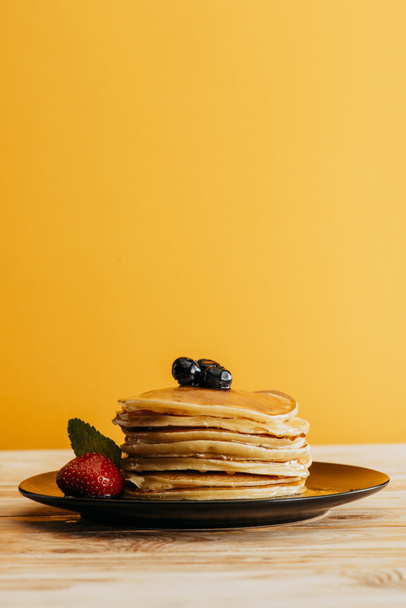 stack of delicious pancakes with berries on yellow - Photo, Image