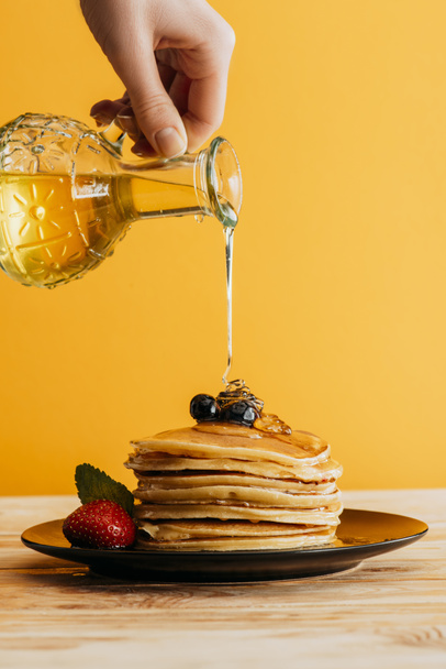 περικοπεί shot από άτομο ρίχνει σιρόπι σφενδάμου πάνω στη στοίβα από pancakes - Φωτογραφία, εικόνα