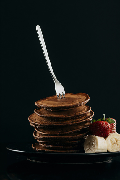 delicious stacked pancakes pierced with fork on black - Photo, Image