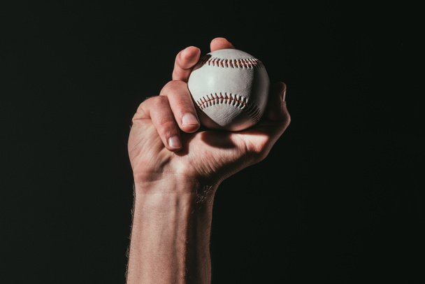 vista parcial del deportista sosteniendo pelota de béisbol aislada en negro
   - Foto, Imagen