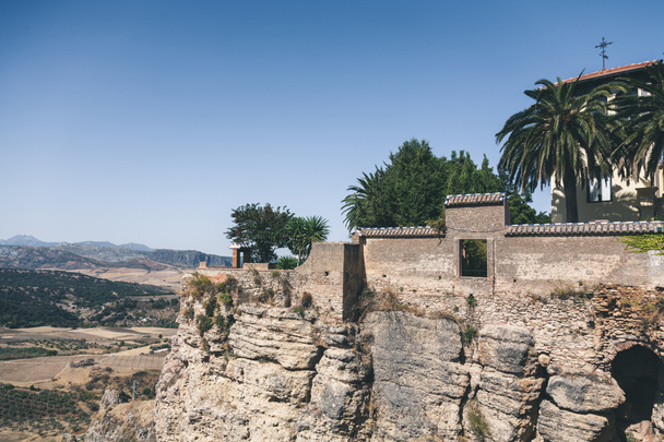 malowniczy widok na kamienne ściany, Palm i budynku na skale przeciwko góry krajobraz, Ronda, Hiszpania - Zdjęcie, obraz