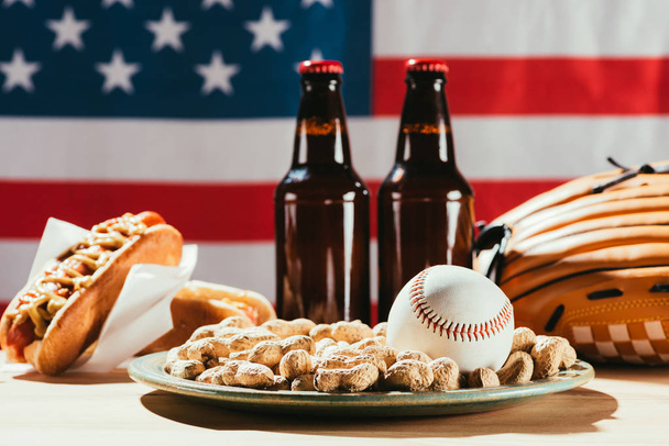close-up view of baseball ball on plate with peanuts and beer bottles - Foto, immagini