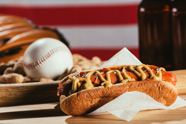 Sosisli sandviç yakından görmek, ahşap masa beyzbol sopası ve spor ekipmanları - Fotoğraf, Görsel
