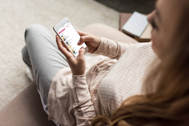 обрізаний знімок жінка на дивані, за допомогою смартфона з itunes app на екрані - Фото, зображення