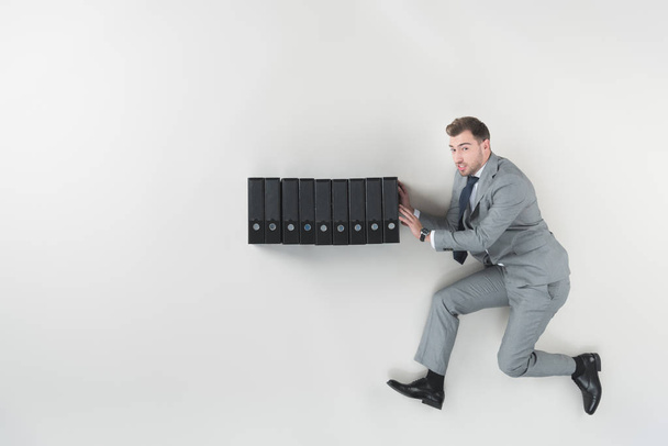overhead view of businessman pushing folders isolated on grey - Foto, Imagem