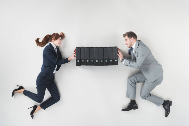 overhead view of smiling businesspeople pushing folders isolated on grey - Foto, immagini