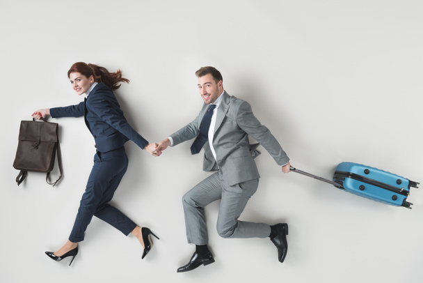 overhead view of business colleagues with baggage holding hands isolated on grey - Photo, Image