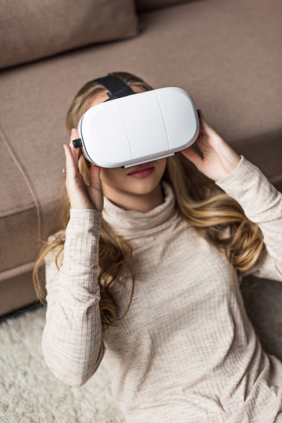 attrayant jeune femme en réalité virtuelle casque à la maison couché sur le sol
 - Photo, image