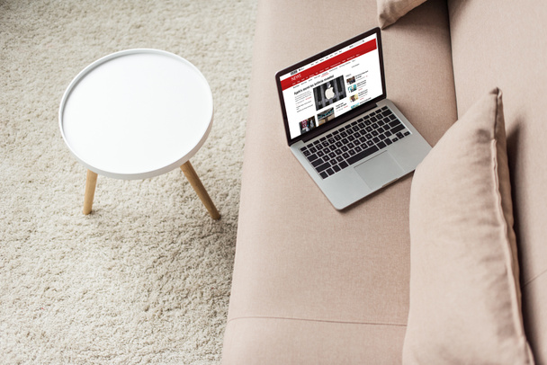 high angle view of laptop standing on cozy couch with bbc website on screen - Фото, изображение