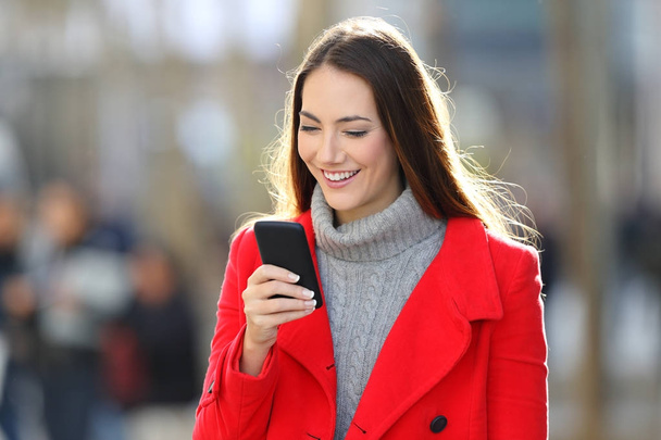 Woman walking and using a smart phone in winter - Zdjęcie, obraz