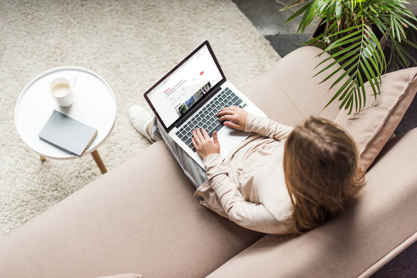 high angle view of woman at home sitting on couch and using laptop with airbnb website on screen - Foto, Bild