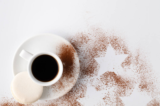 One small cup of cofee and cocoa powder on white table - Фото, изображение