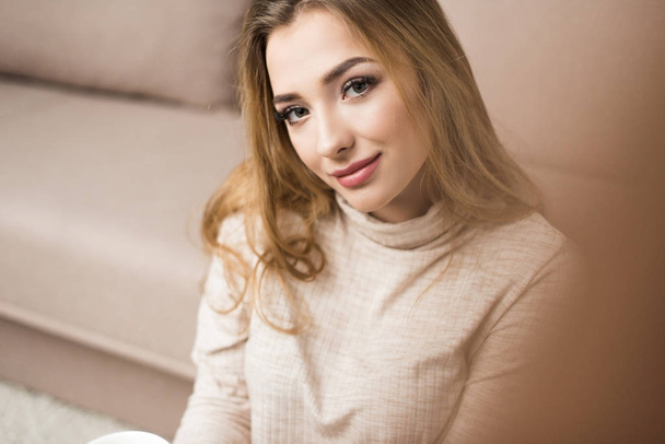 close-up portrait of beautiful young woman in warm sweater at home - Foto, Bild