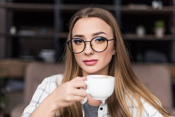 Крупным планом портрет красивой молодой женщины, пьющей кофе
 - Фото, изображение