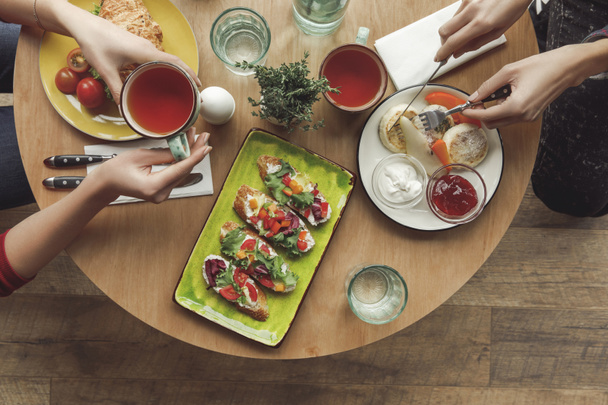 insanlar birlikte kahvaltı ederken çay içmek kadeh kırpılmış - Fotoğraf, Görsel