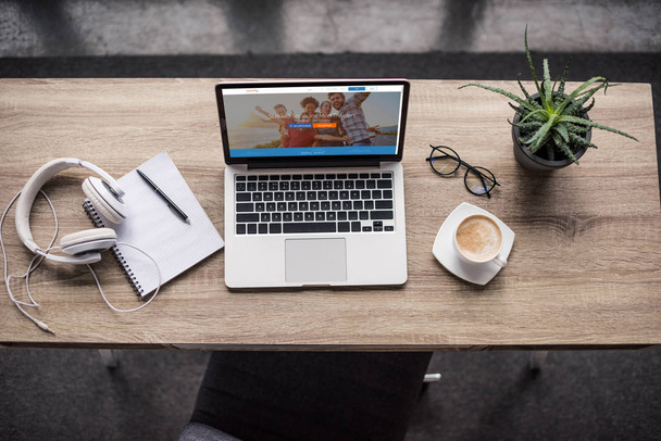 Draufsicht auf den Laptop am modernen Arbeitsplatz mit Couchsurfing-Website auf dem Bildschirm - Foto, Bild
