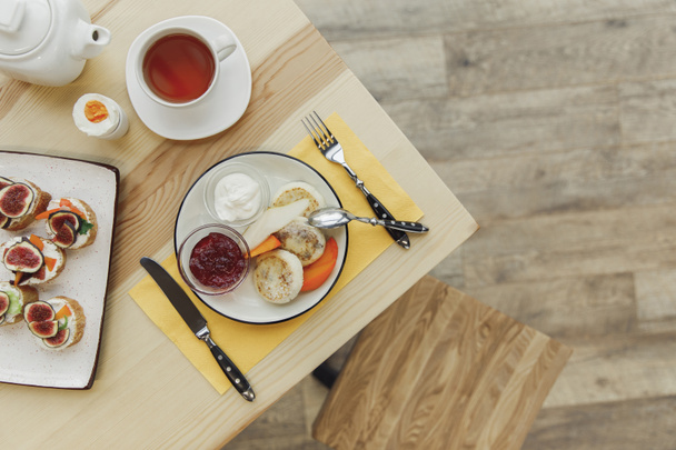 木製のテーブルにお茶セットとおいしい健康的な朝食のトップ ビュー   - 写真・画像