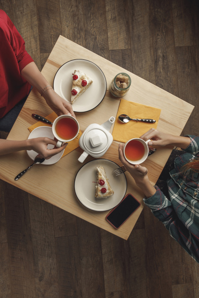 top view of two people drinking tea above table with pastries and smartphone - Fotoğraf, Görsel