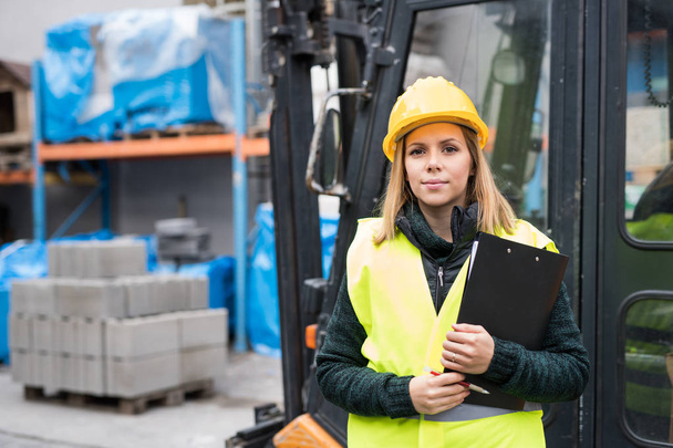 Woman forklift truck driver in an industrial area. - Valokuva, kuva