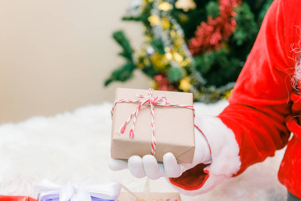 Santa Claus gehandschoende handen met luxe-geschenketui op kamer. Sinterklaas geschenken voor kerst en een rust gebracht door de Bank. Huis decoratie. - Foto, afbeelding