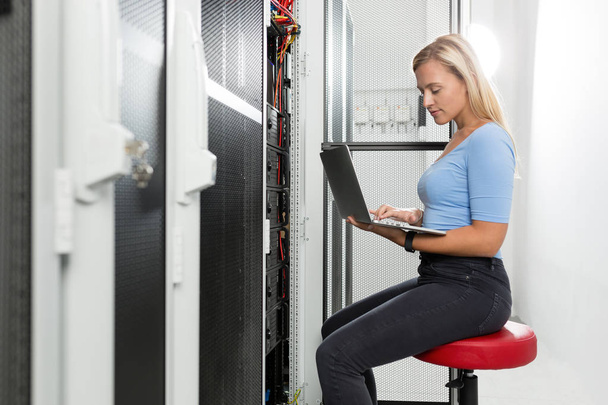Portrait of technician working on laptop in server room - Photo, Image