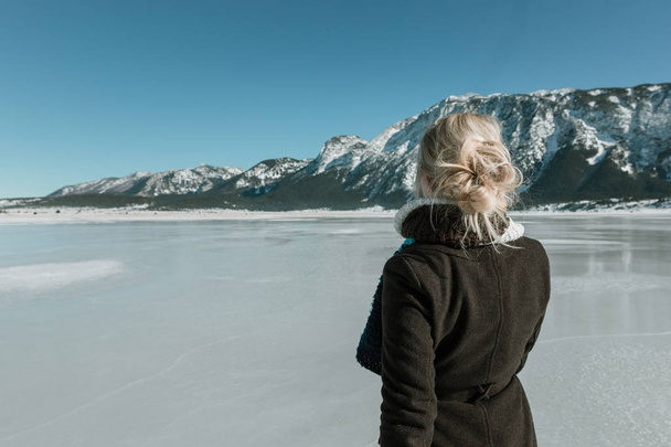rear view of woman looking at mountain and frozen lake - Photo, image