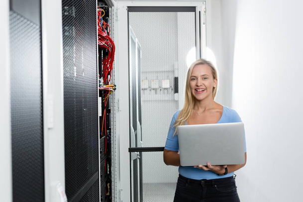 Portrait of technician working on laptop in server room - Photo, image