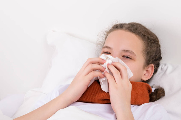 girl in bed blows a snot from her nose into a napkin - Photo, Image