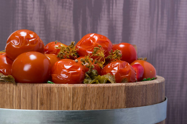 wooden tub with salted tomatoes, on a dark background - Foto, imagen