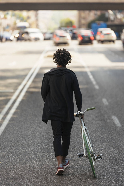 Komea afro mies kävelee hänen pyörä
. - Valokuva, kuva