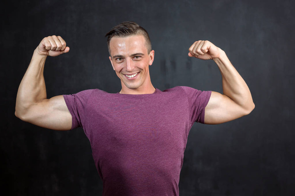 Portrait of an athletic fitness male dressed in a sportswear over grey vignette background. - Foto, afbeelding