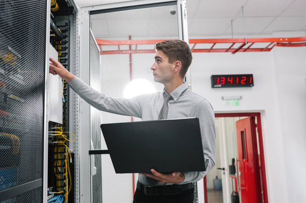 Young business man with laptop working in data center - 写真・画像