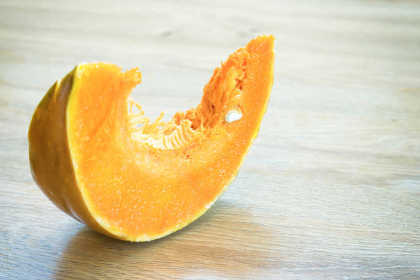 Slice of orange ripe pumpkin on wooden desk - Foto, imagen