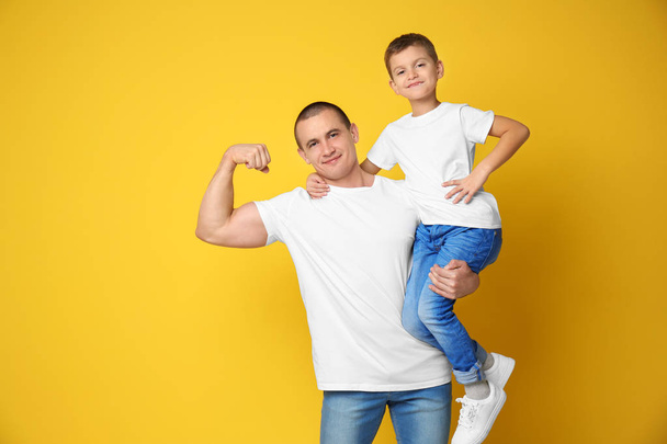 Dad and his son showing muscles on color background - Фото, зображення
