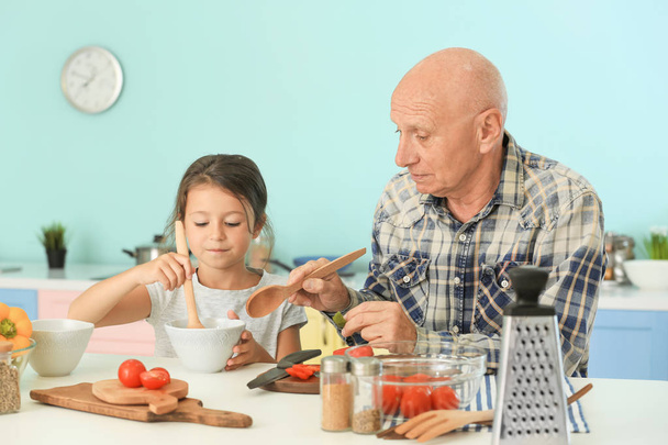 Senior man cooking together with his granddaughter  - Foto, Imagen